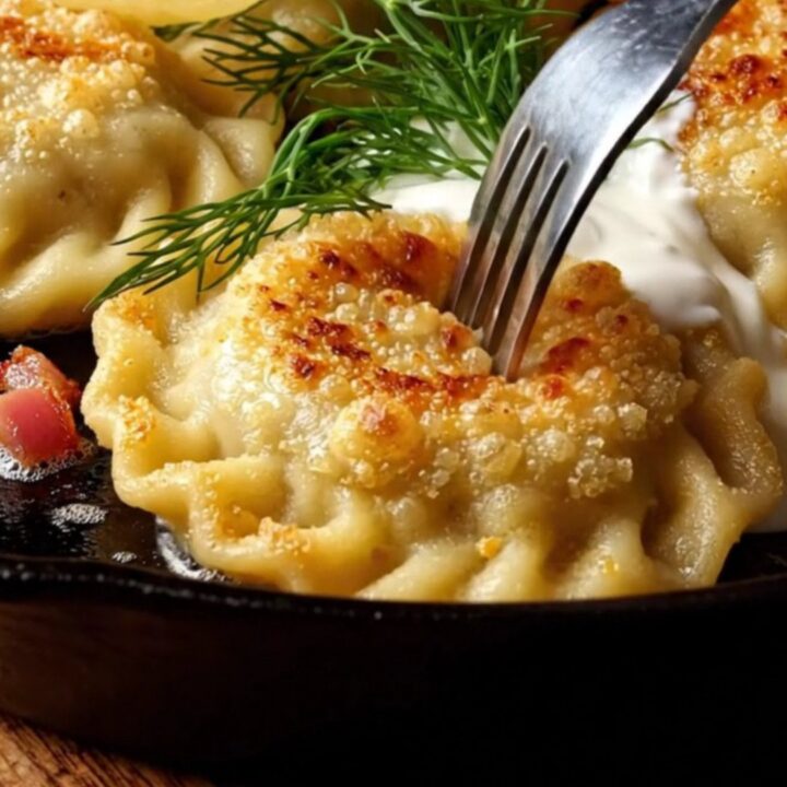 Crispy golden-brown pan-seared pierogi topped with crispy bacon bits, a dollop of sour cream