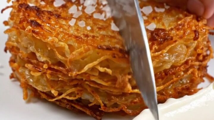 A golden-brown, woven potato stack in a skillet, displaying a crispy, detailed texture.