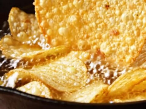 A cast-iron skillet filled with a bubbling, golden loaded baked potato dip topped with melted cheddar, bacon, and scallions.