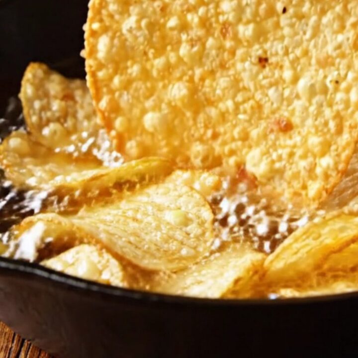 A cast-iron skillet filled with a bubbling, golden loaded baked potato dip topped with melted cheddar, bacon, and scallions.