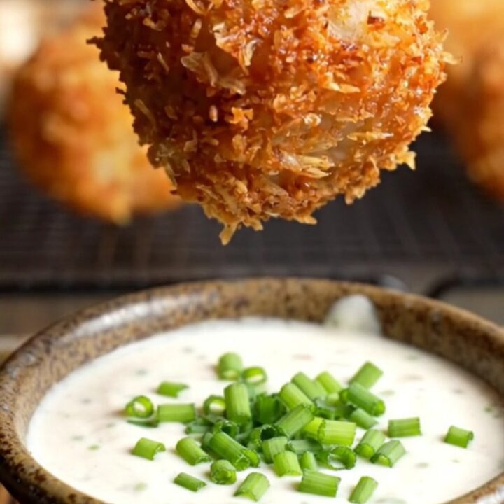 A close-up of a crispy bacon-wrapped tater tot bomb being pulled apart to reveal molten pepper jack cheese.