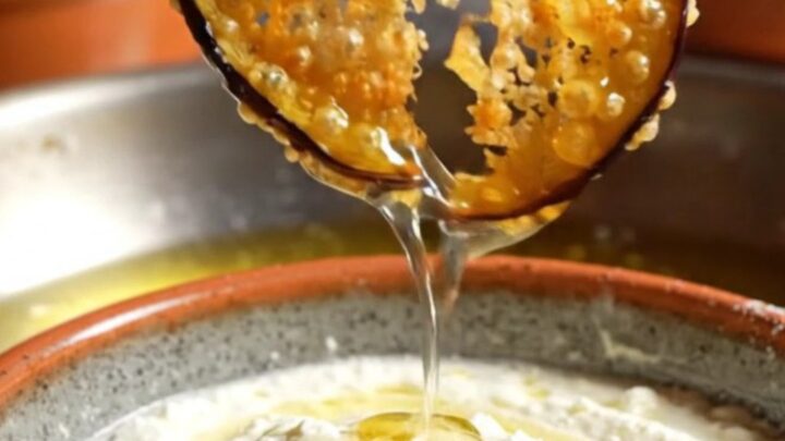 A platter of golden-brown crispy eggplant chips drizzled with honey and served with a bowl of creamy whipped feta.
