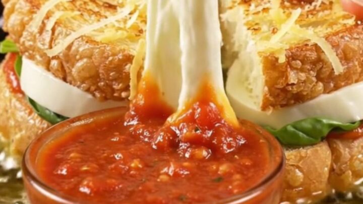 A golden-fried potato-crusted mozzarella sandwich being pulled apart with a long stretch of molten cheese.