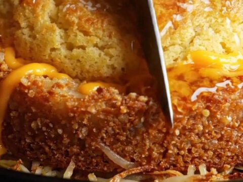 A golden-crusted skillet cornbread sliced into wedges, showing the crispy hashbrown potato bottom and cheesy center.