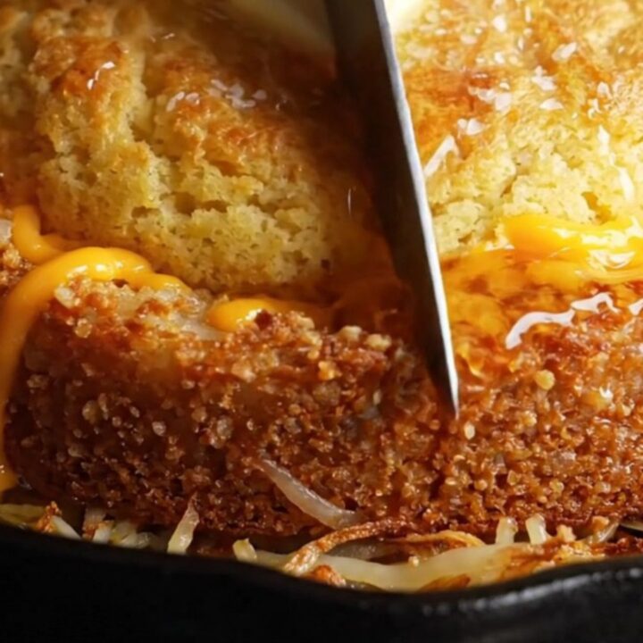 A golden-crusted skillet cornbread sliced into wedges, showing the crispy hashbrown potato bottom and cheesy center.