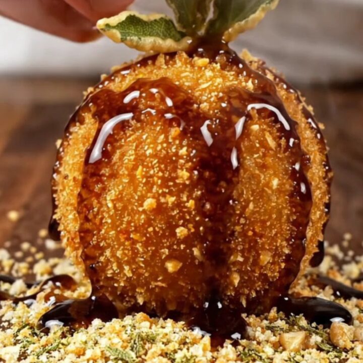 A golden-brown croquette broken open to show a creamy blue cheese and walnut center.