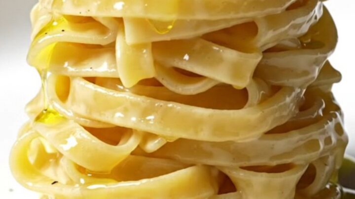 A close-up of perfectly cooked tonnarelli pasta coated in a creamy, pepper-speckled Pecorino Romano sauce.