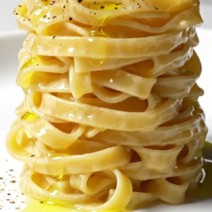 A close-up of perfectly cooked tonnarelli pasta coated in a creamy, pepper-speckled Pecorino Romano sauce.