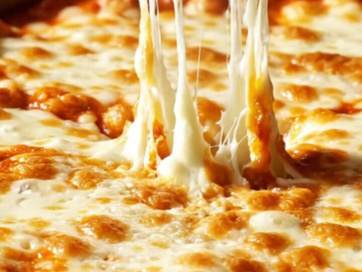 Close-up of jumbo pasta shells filled with creamy ricotta and roasted garlic, bubbling in red marinara sauce.