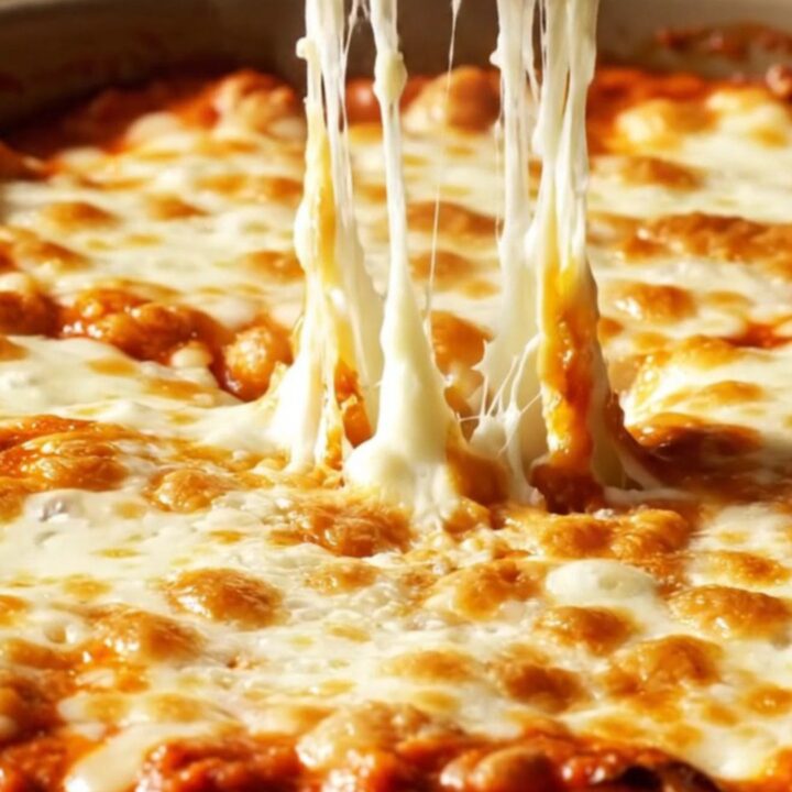 Close-up of jumbo pasta shells filled with creamy ricotta and roasted garlic, bubbling in red marinara sauce.