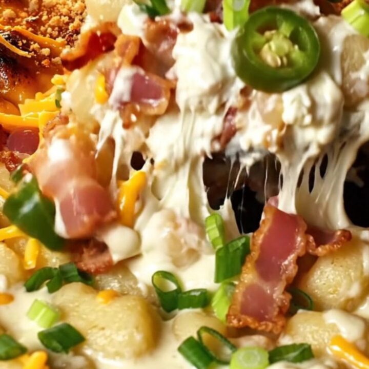 A cast iron skillet filled with creamy gnocchi, crispy bacon bits, and charred jalapenos, topped with golden-brown panko.