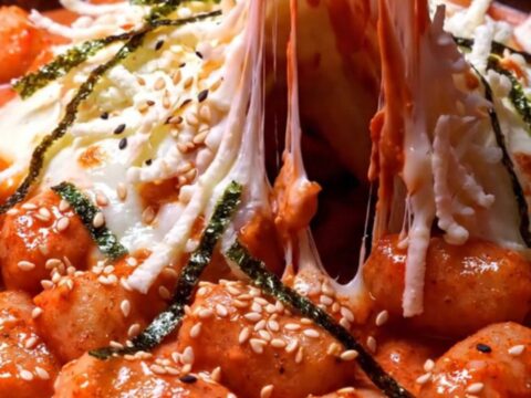 Extreme close-up of chewy potato gnocchi coated in a glossy Korean gochujang rosé cream sauce with melted mozzarella.