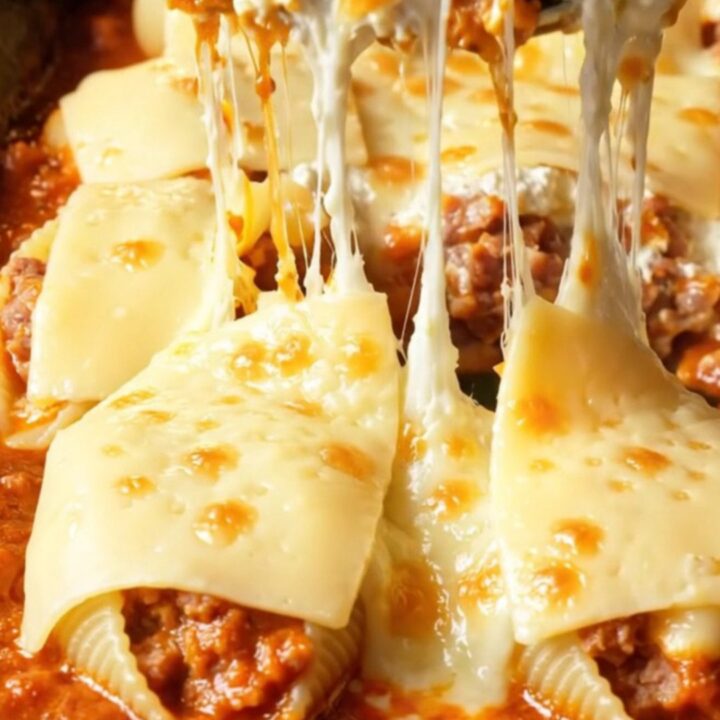 A close-up of jumbo pasta shells stuffed with spicy sausage and ricotta, baked until golden in a garlic marinara sauce.