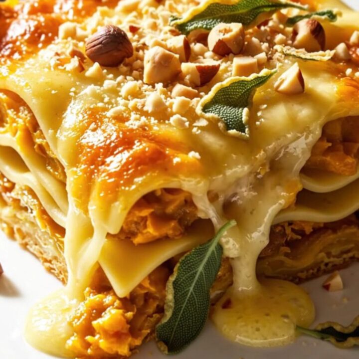 A golden, bubbling slice of butternut squash lasagna topped with toasted hazelnuts and fried sage leaves.