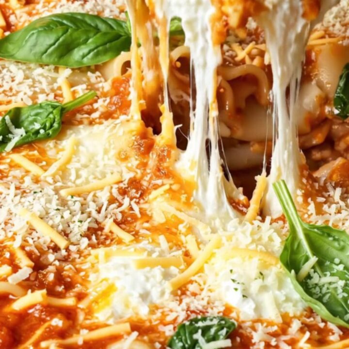 A close-up of a bubbling skillet filled with lasagna, showing melty cheese and fresh spinach.