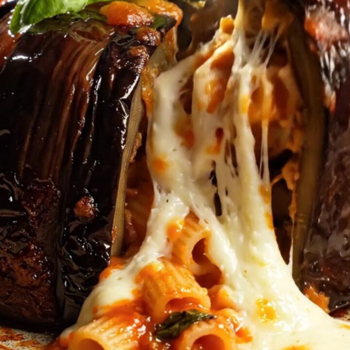 A rustic Sicilian Eggplant Parmigiana Pasta Timbale sitting on a wooden board with fresh basil.