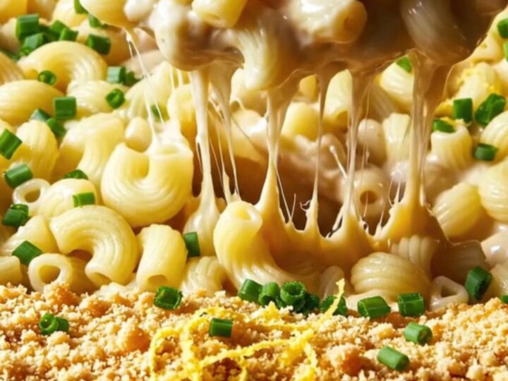A close-up of a bowl of lobster mac and cheese with visible lobster chunks and a golden breadcrumb topping.