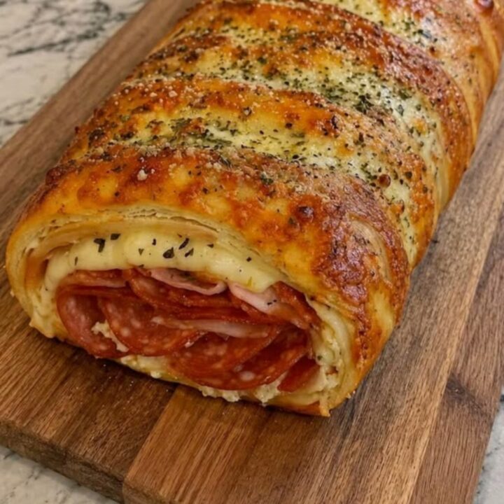 A freshly baked golden brown stromboli sliced open on a rustic wooden board, revealing melted cheese and pepperoni.