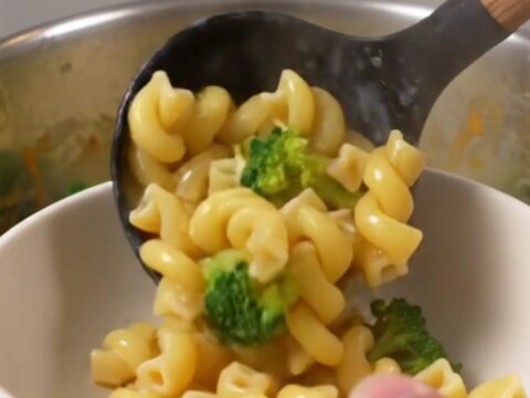 A large pot filled with creamy broccoli cheddar cavatappi, showcasing the vibrant green broccoli and smooth cheese sauce.