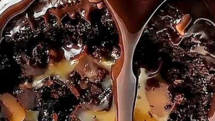A close-up of a chocolate turtle cake roll with caramel and pecans, topped with glossy chocolate ganache.