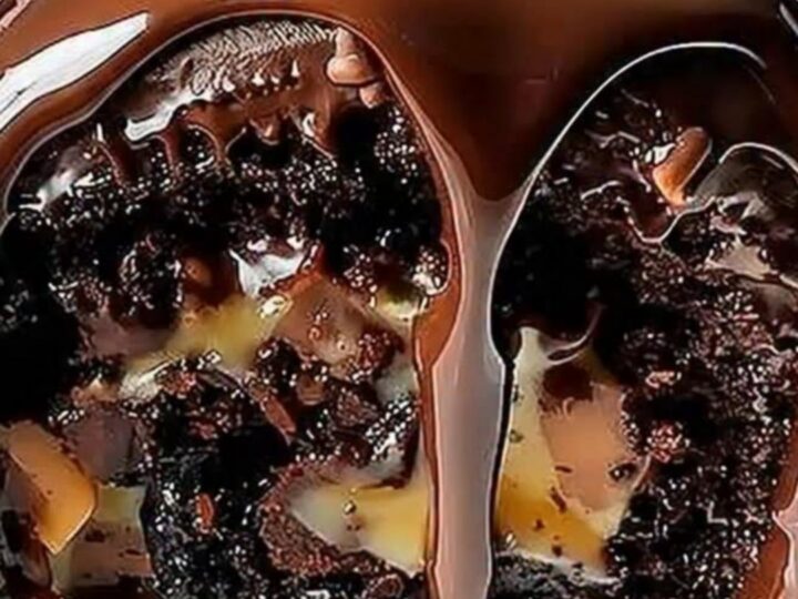 A close-up of a chocolate turtle cake roll with caramel and pecans, topped with glossy chocolate ganache.