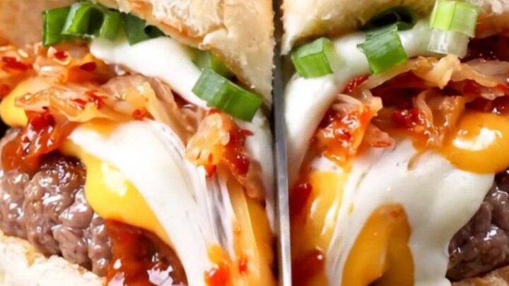 A close-up of a juicy smash burger with a glossy gochujang glaze, melted cheese, and kimchi on a toasted milk bread bun.
