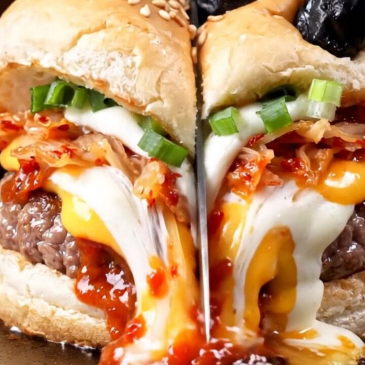 A close-up of a juicy smash burger with a glossy gochujang glaze, melted cheese, and kimchi on a toasted milk bread bun.
