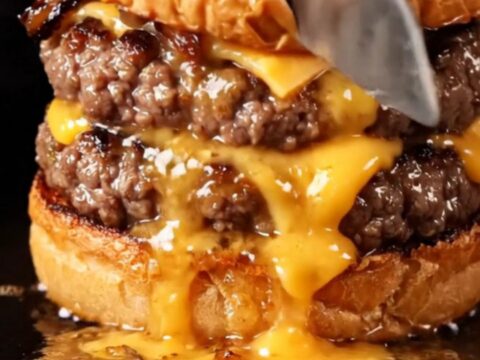 A close-up of a juicy Wagyu smash burger on a brioche bun with roasted bone marrow dripping over the side.