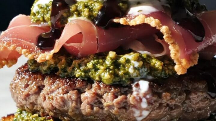 A gourmet Italian-style smash burger topped with a whole ball of burrata and crispy prosciutto on a toasted bun.
