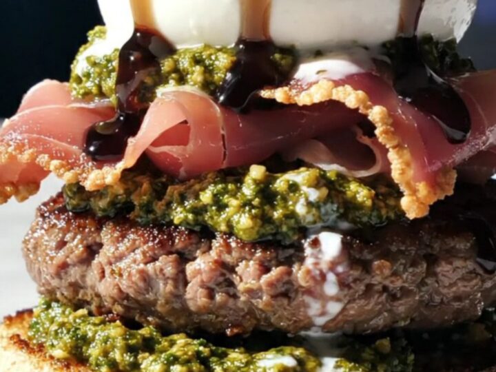 A gourmet Italian-style smash burger topped with a whole ball of burrata and crispy prosciutto on a toasted bun.