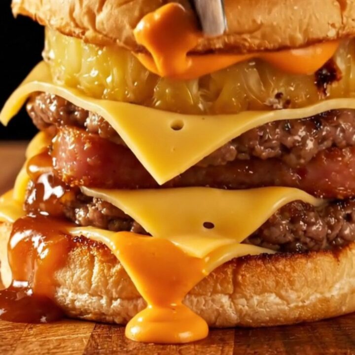 A close-up of a juicy Hawaiian smash burger with charred pineapple, crispy Spam, and glossy teriyaki glaze on a toasted bun.