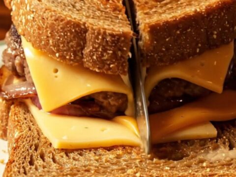 Golden-brown marble rye patty melt with stretching cheese pull and caramelized onions.