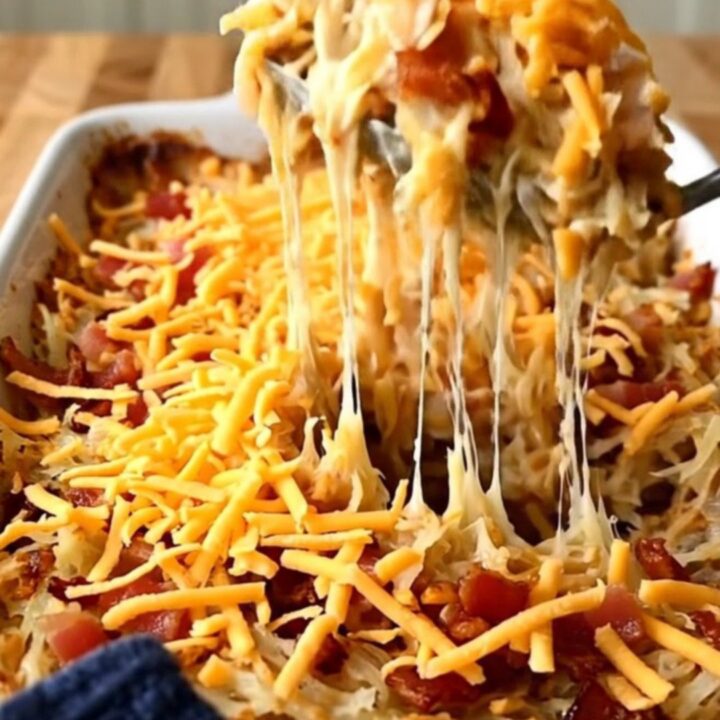 A top-down view of a creamy bacon ranch hash brown casserole in a white baking dish ready for the oven.