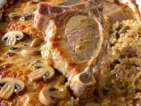 A top-down view of a rectangular baking dish filled with pork chops and rice in a creamy mushroom sauce.