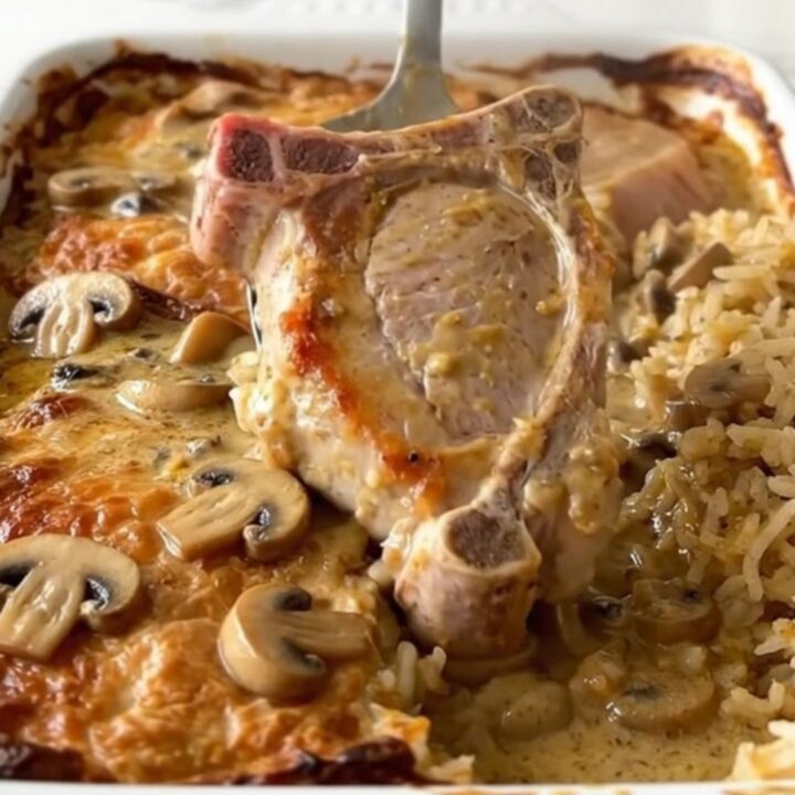 A top-down view of a rectangular baking dish filled with pork chops and rice in a creamy mushroom sauce.