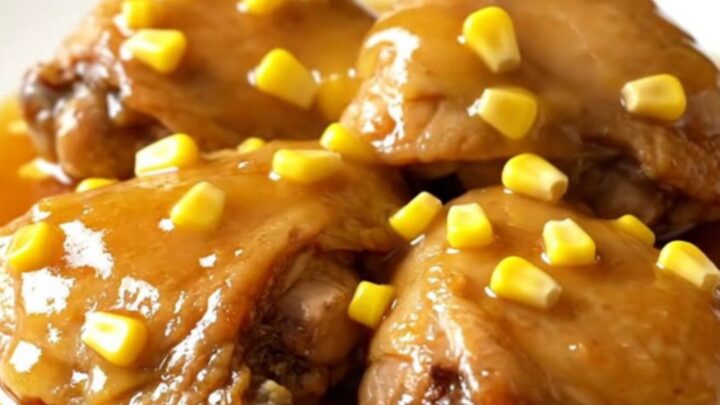 A plate of tender slow-cooked honey butter chicken thighs served with corn kernels and a glossy sauce.