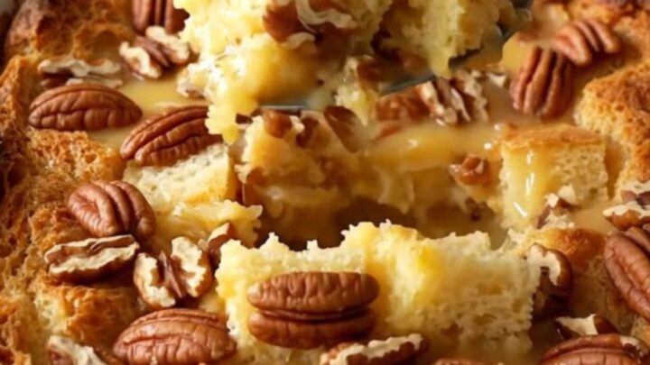 A large white ceramic baking dish filled with golden, toasted pecan pie bread pudding on a quartz counter.