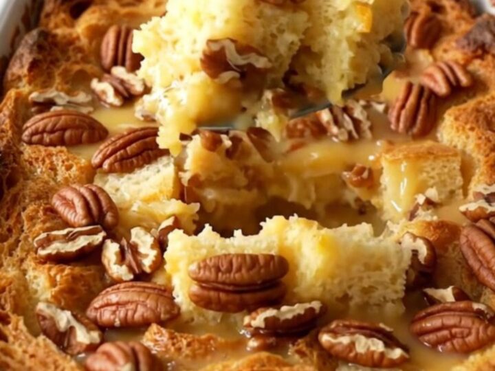 A large white ceramic baking dish filled with golden, toasted pecan pie bread pudding on a quartz counter.