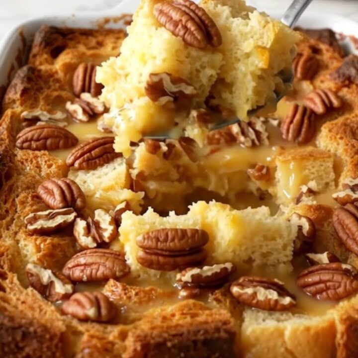 A large white ceramic baking dish filled with golden, toasted pecan pie bread pudding on a quartz counter.