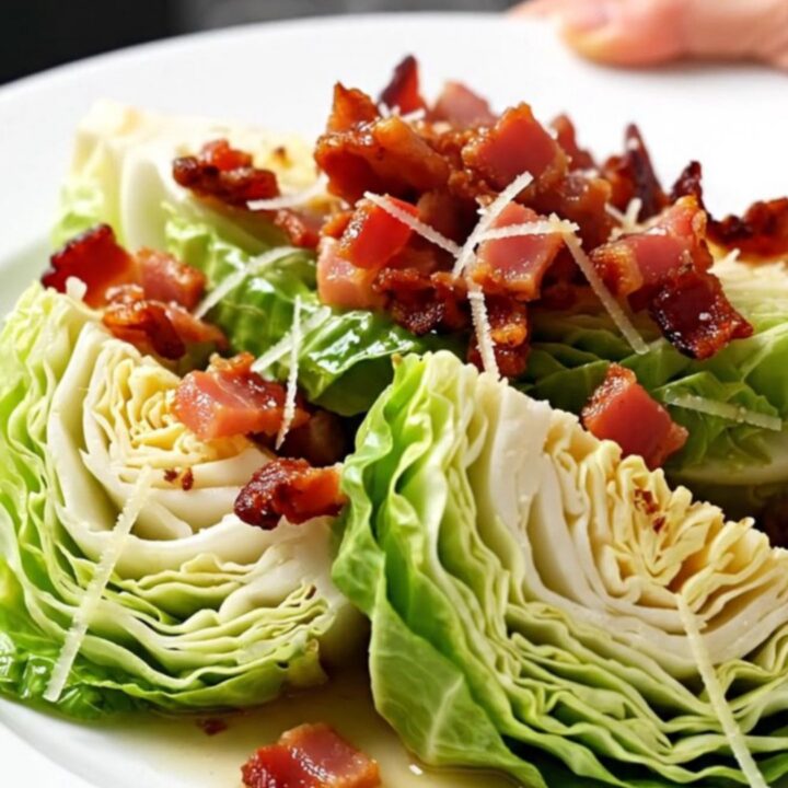 A top-down view of green cabbage wedges in a slow cooker topped with bacon and parmesan.