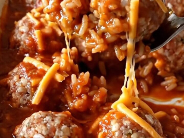 A rectangular ceramic dish filled with baked turkey and rice meatballs covered in bubbling tomato sauce and melted golden