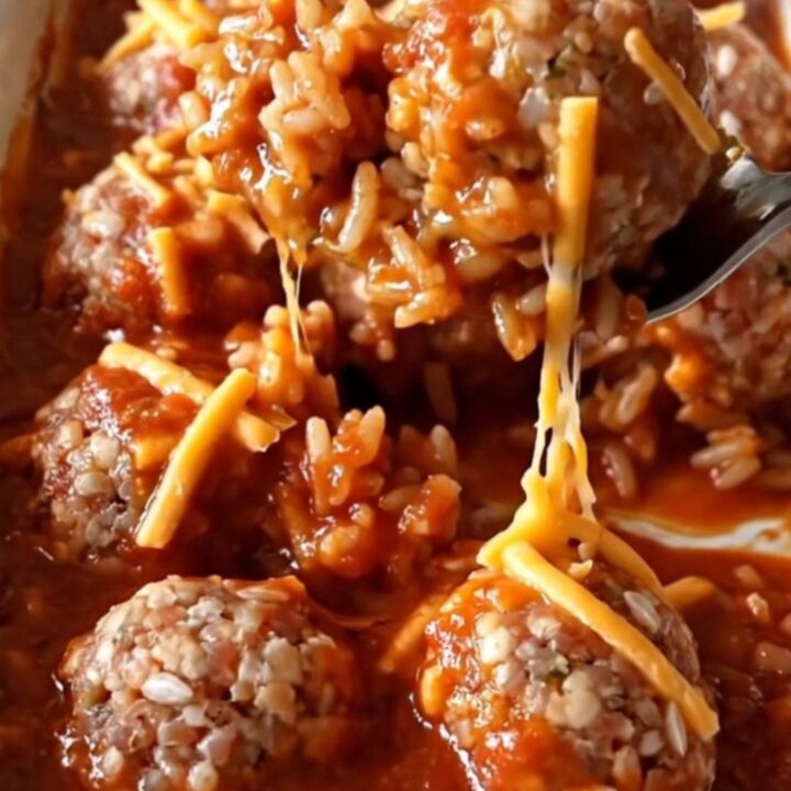 A rectangular ceramic dish filled with baked turkey and rice meatballs covered in bubbling tomato sauce and melted golden