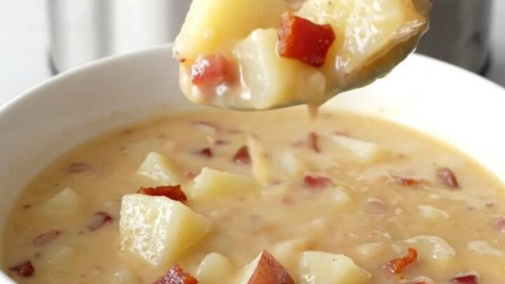 A steaming bowl of creamy potato soup topped with bacon and cheddar cheese.
