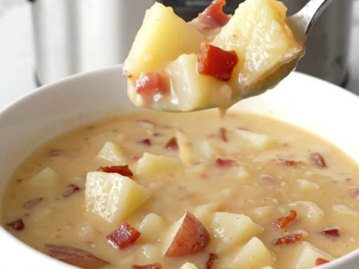 A steaming bowl of creamy potato soup topped with bacon and cheddar cheese.