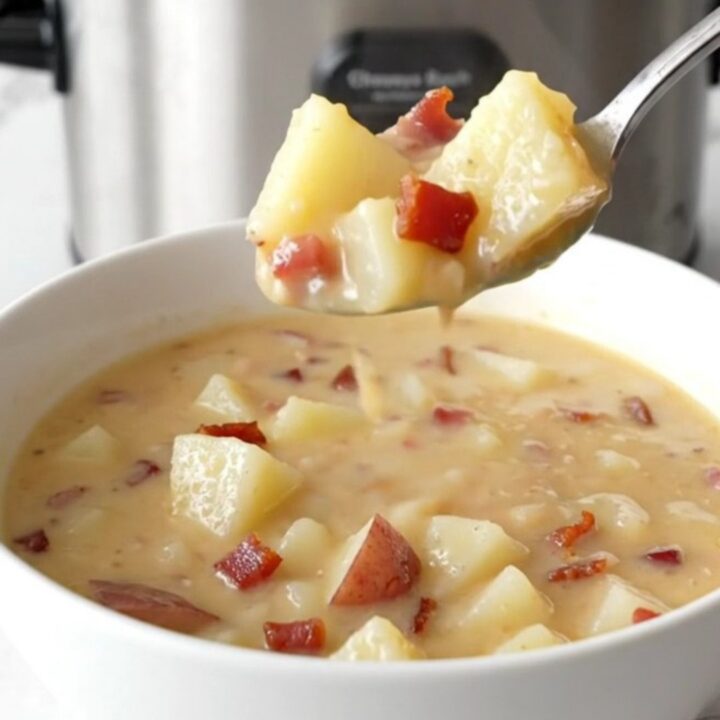 A steaming bowl of creamy potato soup topped with bacon and cheddar cheese.