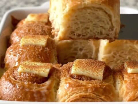 A golden-brown Hawaiian roll French toast bake in a white ceramic dish on a speckled countertop.