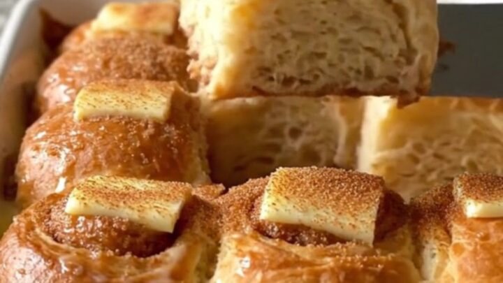 A golden-brown Hawaiian roll French toast bake in a white ceramic dish on a speckled countertop.