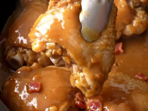 Slow cooker chicken thighs glazed in a rich brown sugar, butter, and bacon sauce in a stoneware insert.