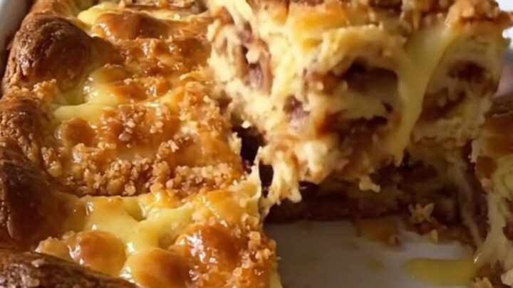 A golden brown eggnog cinnamon roll bake in a white ceramic dish on a speckled countertop.