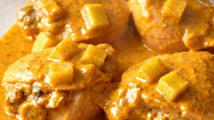 A close-up shot of creamy buffalo chicken thighs served on a white plate with visible celery pieces.